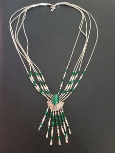 Beautiful vintage piece of Native American jewelry. The necklace is a 5 strand liquid silver necklace. At it's center, it has a malachite stone mounted into sterling silver scalloped setting. Towards the center of the necklace, each strand has malachite and sterling silver beads. From the scalloped edges, the pendant has 7 fringes dangling, each fringe has sterling silver and malachite beads. The necklace is 20 inches long. Southwestern Silver Gemstone Necklaces, Southwestern Silver Necklaces With Gemstones, Silver Southwestern Necklace With Gemstone, Southwestern Style Silver Gemstone Necklaces, Silver Southwestern Style Gemstone Necklace, Sterling Silver Beaded Multi-strand Jewelry, Vintage Multi-strand Jewelry With Natural Stones, Elegant Silver Malachite Jewelry, Sterling Silver Multi-strand Beaded Jewelry