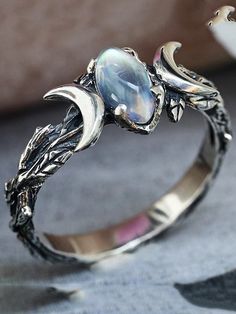 a silver ring with an opal stone in the center and leaves on it's sides