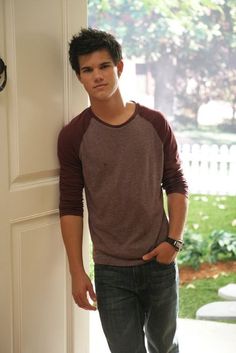 a young man standing in front of a door with his hand on his hip and looking at the camera