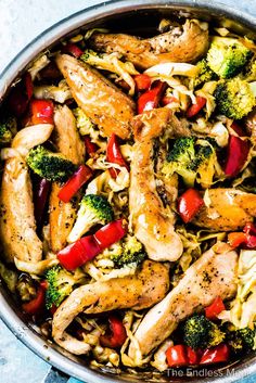 a pan filled with chicken, broccoli and red peppers on top of it