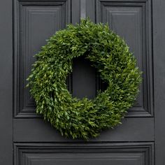 a black door with a green wreath on it