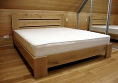 a wooden bed frame in a room with wood flooring and white sheets on it