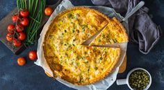 a quiche with cheese and vegetables on the side