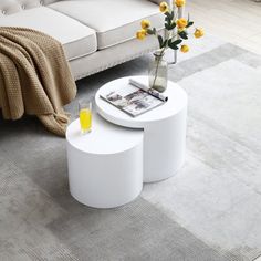 a living room with white furniture and yellow flowers in vases on the coffee table