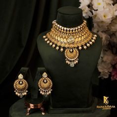 a gold necklace and earring set with matching earrings on display in front of flowers