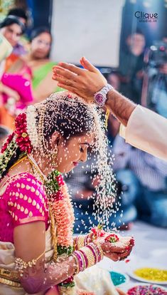 a woman in a pink sari is pouring water on her face and hands as she holds