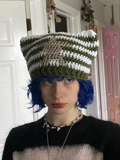 a woman with blue hair wearing a green and white knitted hat on her head