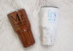 two personalized tumblers sitting next to each other on a white fur covered surface