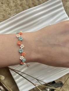 a woman's arm with an orange, white and blue beaded bracelet on it