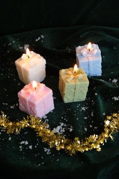 three candles are sitting next to each other on a black surface with gold tinsel