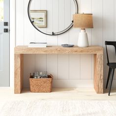 a wooden table with a lamp and a round mirror on the wall next to it