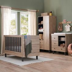 a baby's room with green walls and wooden furniture