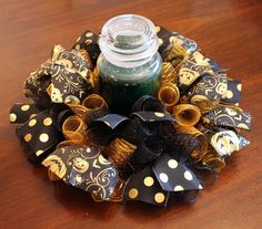 a candle is sitting on top of a black and gold wreath with polka dot bows