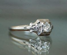 an antique diamond engagement ring on a reflective surface