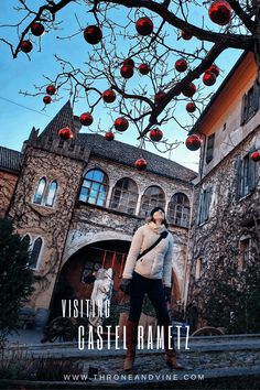 a woman standing in front of an old building with red ornaments hanging from the tree