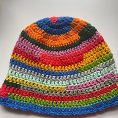 a multicolored crocheted hat is laying on a white surface