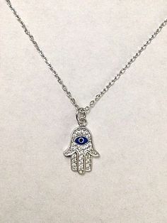 "925 STERLING SILVER HAMSA AND EVIL EYE PENDANT . HAMSA AND EVIL EYE FOR PROTECTION AND GOOD LUCK. 18\" TO 20\" ADJUSTABLE CHAIN. PENDANT SIZE 15 mm X 10 mm CADENA DE 925 PLATA ESTERLINA MANO DE FATIMA Y OJO DE LA BUENA SUERTE. LA MANO DE FATIMA Y OJO PARA BUENA SUERTE Y PROTECCION. 18\" A 20\" CADENA AJUSTABLE. TAMAÑO DEL DIJE : 15 mm X 10 mm" Symbolic Sterling Silver Dangle Charm Necklaces, Symbolic Sterling Silver Charm Necklace With Adjustable Chain, Spiritual Sterling Silver Charm Necklace With Adjustable Chain, Symbolic Sterling Silver Good Luck Charm Necklace, Sterling Silver Symbolic Jewelry For Good Luck, Symbolic Sterling Silver Jewelry For Good Luck, Symbolic Silver Necklaces With Adjustable Size, Symbolic Silver Charm Necklace With Adjustable Chain, Silver Symbolic Charm Necklace With Adjustable Chain