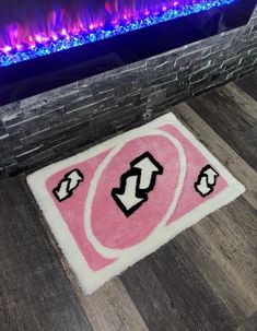 a pink rug with black and white letters on it in front of an electric fireplace