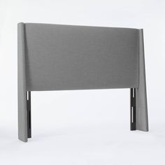 an upholstered headboard with metal legs on a white background in front of a plain backdrop