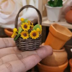 a hand holding a small basket with sunflowers in it