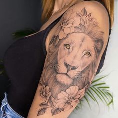 a woman's arm with a lion and flowers tattoo on her left shoulder, next to a plant