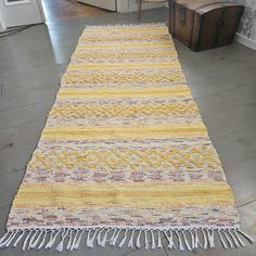 a yellow and white rug with fringes on the floor in front of a door