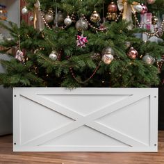 a christmas tree with ornaments hanging from it's branches in front of a white box