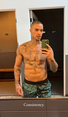 a shirtless man taking a selfie in front of a mirror with his cell phone