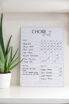 a close up of a plant on a shelf next to a chore chart board