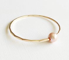 This lovely bangle is make with precious metal wires and pastel pink Edison pearls. Bangle is hand- formed, hammered into a scalloped design and polished for a stunning texture and shine. It looks great worn alone or paired with other shell and charm bangles to create a chic, fun beachy look. Metallic pink Edison pearl is 10-11mm. As you can see in the photos there are naturally occurring blemishes that give these pearls character. These are stock photos so please note pearls are vary in shape a Pink Pearl Bracelet, Charm Bangles, Edison Pearls, Pearl Bangle, Pearl Pink, Metallic Pink, Charm Bangle, Pink Pearl, Metal Wire