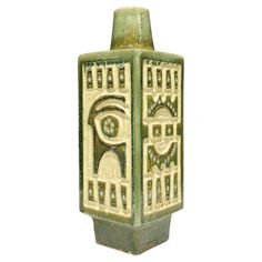 a green vase with an egyptian design on it