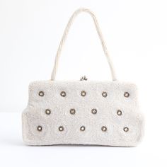 This darling 1950's full beaded handbag with rhinestone accents, is the perfect statement accessory.  The rectangular shape of the bag boasts an ivory bead covered base in a rippled design and claw set rhinestone accents surrounded by grey bugle beads that set off the silver toned metal kiss lock clasp. This is framed by a fully embellished ivory bead handle. The bag opens to a cream rayon satin lining, with one side pocket and a small mirror.  Measurements Height of Bag: 4.2 inches Length: 8 in Handheld Beaded Beige Evening Bag, Beige Beaded Handheld Evening Bag, Vintage Shoulder Bag With Pearl Handle For Everyday, Chic Rectangular Bags For Vintage Events, Chic Rectangular Bag For Vintage Events, Vintage Embellished Clutch Shoulder Bag, Vintage Embellished Shoulder Bag For Wedding, Vintage Embellished Wedding Shoulder Bag, Vintage Beaded Clutch Bag