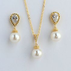 Classic cubic zirconia and pearl bridal  jewelry set in gold plated brass setting includes#Gold tone earrings feature teardrop clear cubic zirconia ear post and 10mm Swarovski pearl dangle drop. Total length of the earrings is 2.7 cms.  #Classic pearl bridal necklace and pendant set with gold plated brass peg and bail.  Necklace features a pendant with 10mm Swarovski single pearl drop that dangles from gold plated brass peg and cubic zirconia bail. Length of the gold plated chain is 18 inches an Elegant Pearl Drop Jewelry Set With Cubic Zirconia, Formal Pearl Drop Jewelry Sets With Cubic Zirconia, Gold Pearl Drop Jewelry With Cubic Zirconia, Anniversary Jewelry Sets With Pearl Drop And Cubic Zirconia, Gold Cubic Zirconia Teardrop Bridal Necklace, Elegant Gold Drop Jewelry Set, Gold Pear-shaped Cubic Zirconia Bridal Earrings, Gold Pearl Drop Jewelry Sets For Anniversary, Gold Plated Drop Jewelry For Wedding