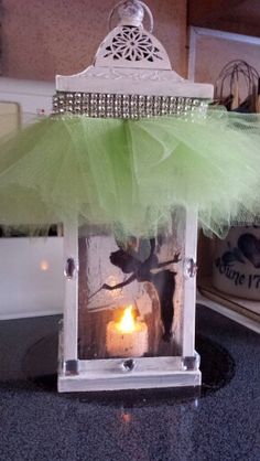 a small white lantern with a green tulle on it