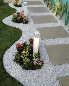 a walkway made out of stones and gravel with flowers in the middle on each side