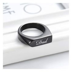 a black ring with the word dad written on it sitting on top of a white surface