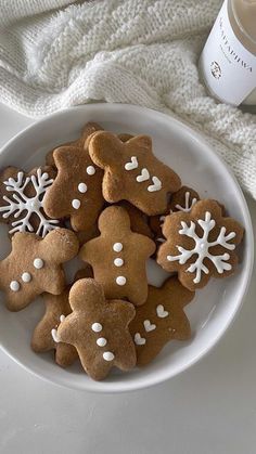 a white plate topped with cut out gingerbread cookies next to a cup of coffee