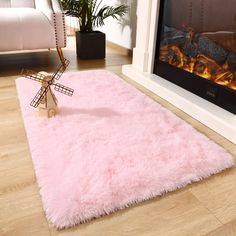 a pink area rug in front of a fireplace with a windmill on the floor next to it