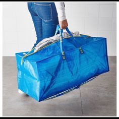 a person holding a blue bag with clothes in it and the bottom part of their pants