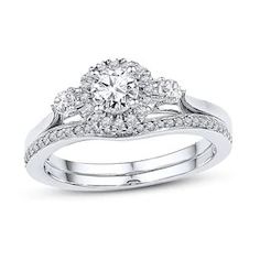 a white gold ring with two diamonds on the band and an oval shaped diamond in the center