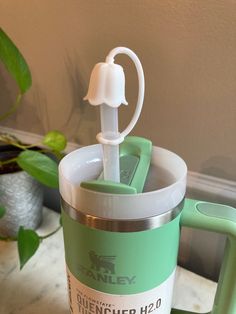 a green and white blender sitting on top of a counter next to a potted plant