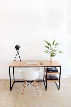 an office desk with a laptop on it and a potted plant next to it