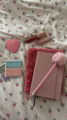 the contents of a pink notebook, pen and other items are laid out on a bed