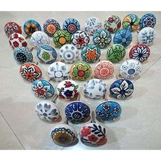 a bunch of different colored glass knobs on a table with white tile flooring