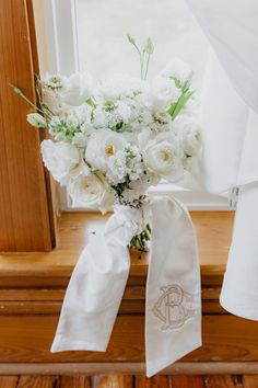 a bouquet of white flowers sitting on top of a window sill next to a curtain