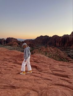 a man standing on top of a red rock covered hillside