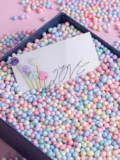 a box filled with lots of colorful candies next to a sign that says love