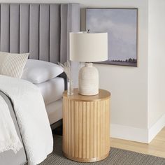 a bedroom with a bed, nightstand and lamp on the side table in front of it