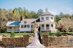 a bride and groom standing in front of a house