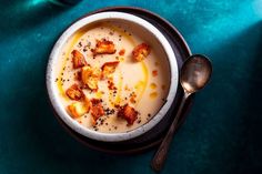 there is a bowl of soup with croutons in it and a spoon on the side